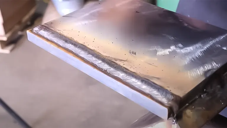 Smooth, straight welding bead on the corner of a metal plate, demonstrating stick welding technique
