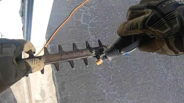 First-person perspective of someone in camouflaged gloves holding a spiked tool over a concrete surface.