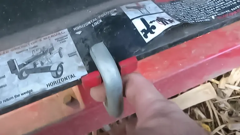 Hand adjusting the control lever on a log splitter with instructional label in the background