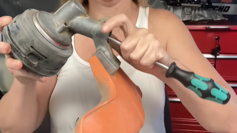 Person using screw driver fixing a stuck trimmer head