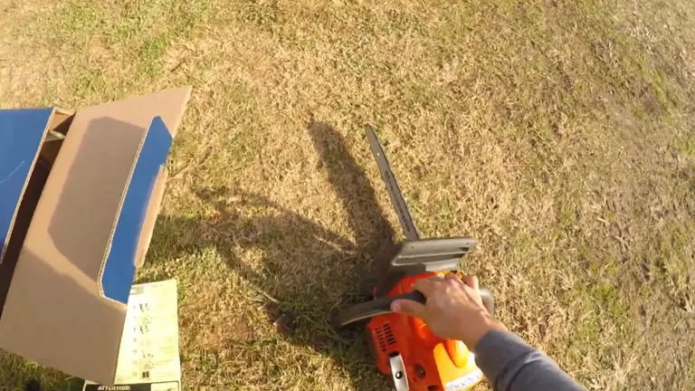Person holding Husqvarna 240 laying on the grass with box in left side