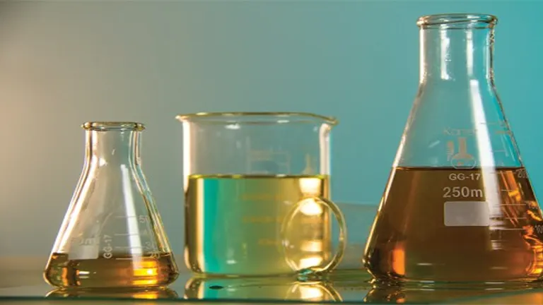 Laboratory glassware with colored liquids on a turquoise background.