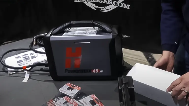 The Hypertherm Powermax45 XP plasma cutter on a table with its cables alongside product manuals and packaging
