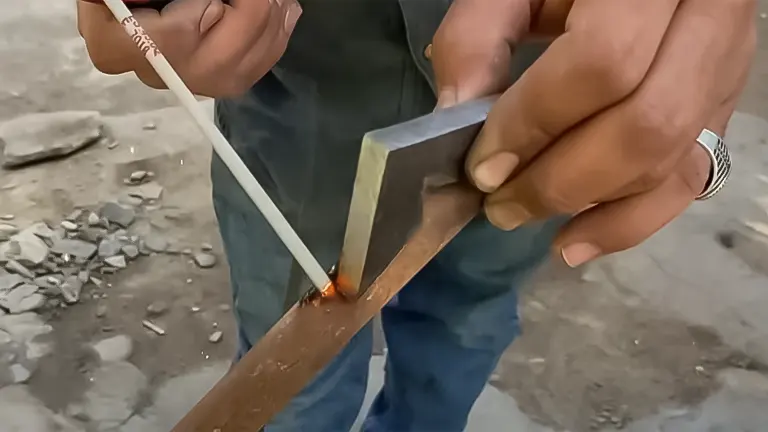 Person initiating a weld with a 7018 electrode on a metal piece