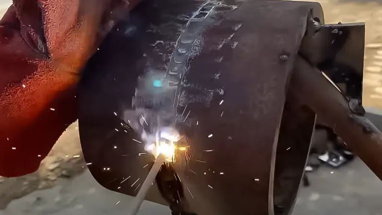 Active welding on a pipe with a 7018 electrode, sparks flying from the contact point