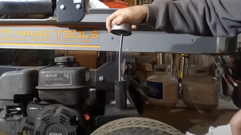 A person operating a Dirty Hand Tools log splitter, with a focus on the hydraulic system handle, relevant to oil and hydraulic fluid maintenance