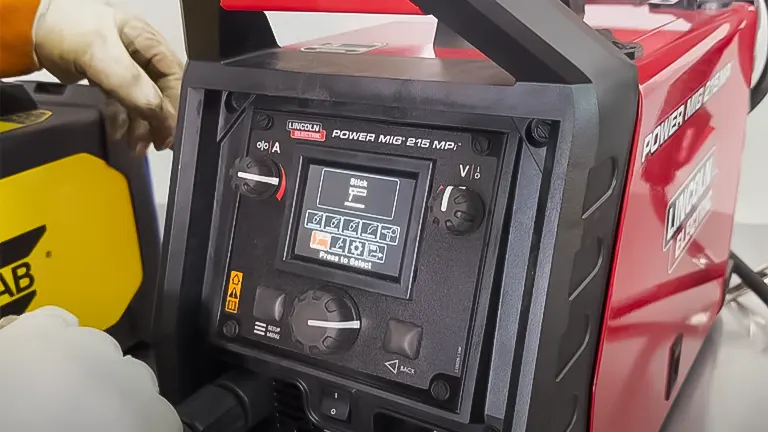 Hand adjusting settings on a Lincoln POWER MIG 215 MP welding machine