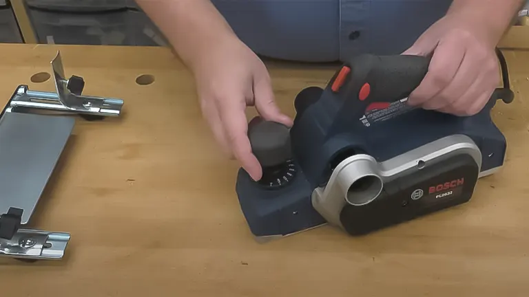 Hands adjusting the depth on a Bosch electric hand plane on a woodworking bench