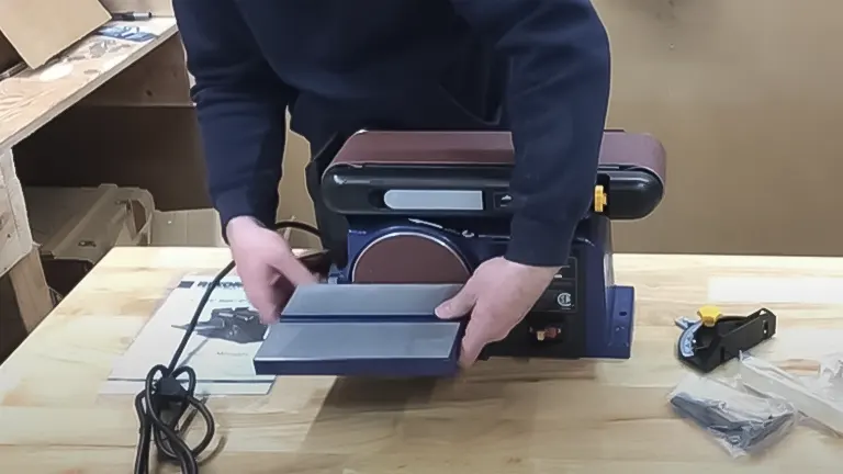 Person setting up the work table on a Rikon 50-112 belt and disc sander