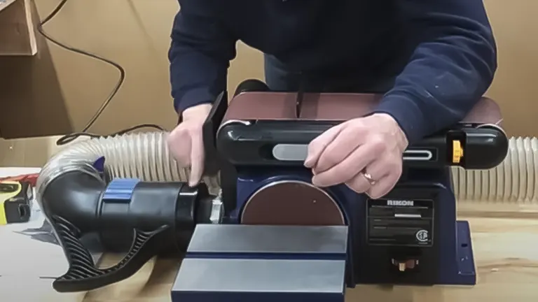 Individual connecting a dust extraction hose to a Rikon 50-112 belt and disc sander