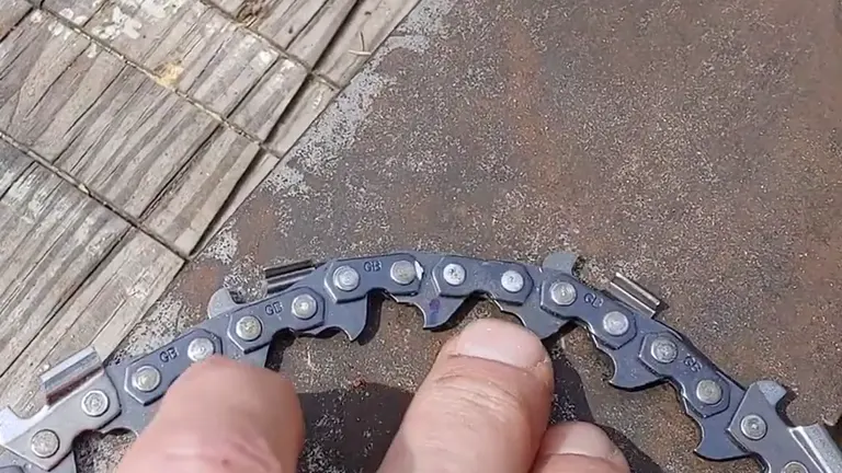 person holding a chainsaw chain, inspecting its fit and test