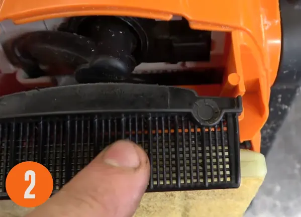 Close-up of a hand adjusting the mode on an orange Stihl MS 290 chainsaw
