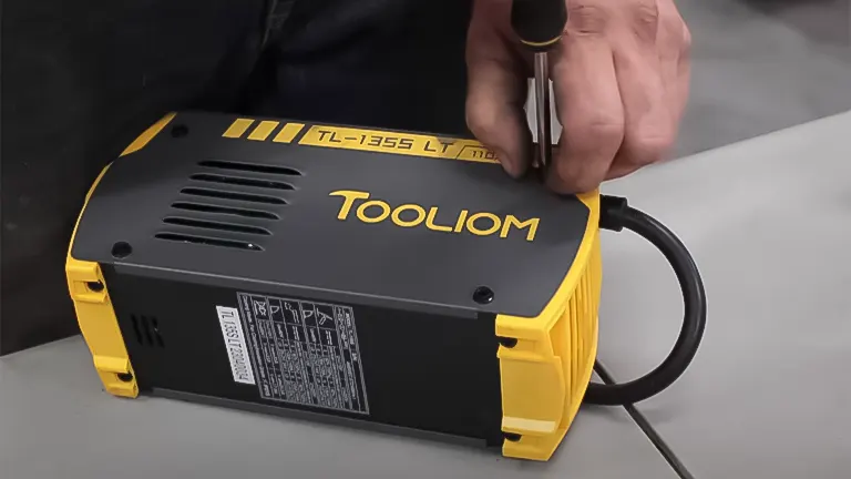 Hand adjusting a TOOLIOM TL-135S Stick Welder with a yellow and black casing