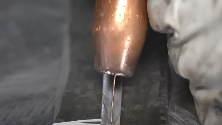 MIG welding torch in action with a visible welding wire and a gloved hand