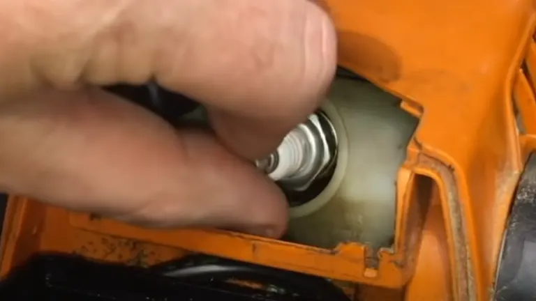 Person removing chainsaw spark plug 