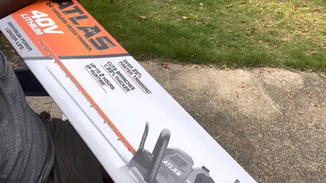 Person holding an ATLAS 40V Lithium-Ion Brushless Chainsaw box in an outdoor setting