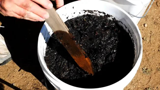 Person stirring black liquid with a stick