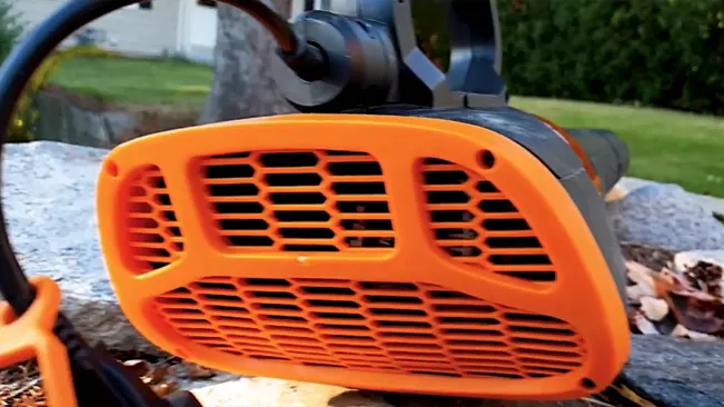 Close-up of orange leaf blower intake with leaves and debris.