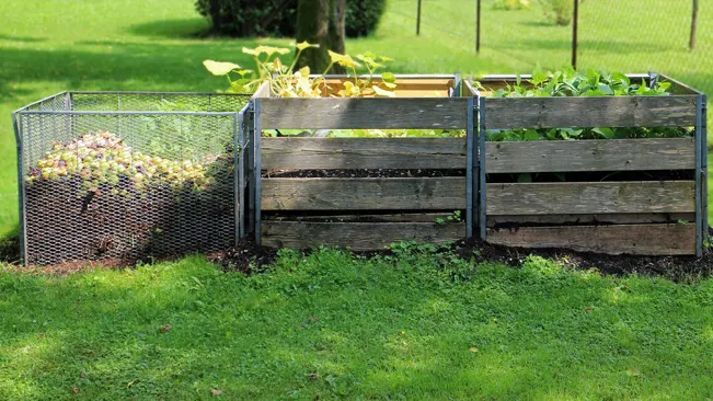 Two wooden compost bins in a field