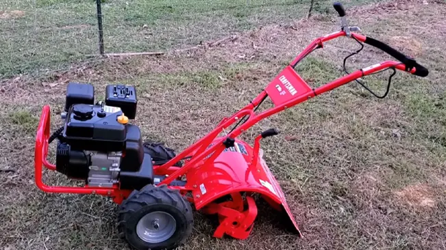 well-maintained red tiller on a grassy outdoor area, equipped with sturdy wheels and essential controls for operation.