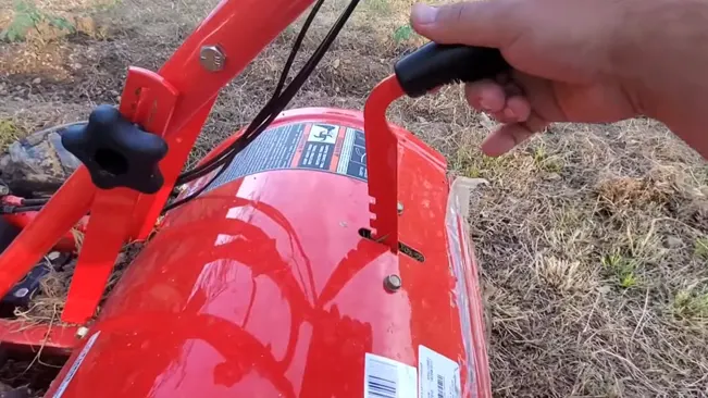 hand pulling the starter cord of a red wood chipper outdoors.