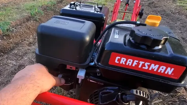 Person operating a red CRAFTSMAN tiller on a field