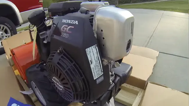 Honda GC 160 engine mounted on a structure, surrounded by cardboard boxes