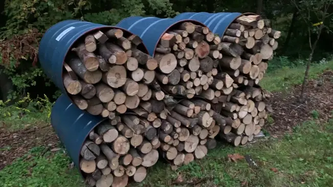 Stacked firewood in blue metal holders outdoors