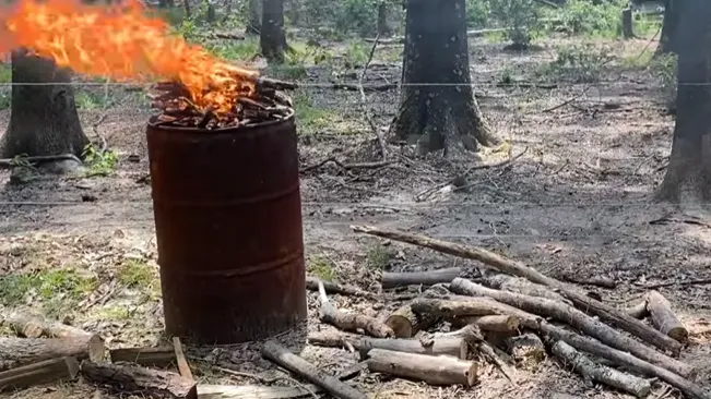Burning wooden barrel in forest.