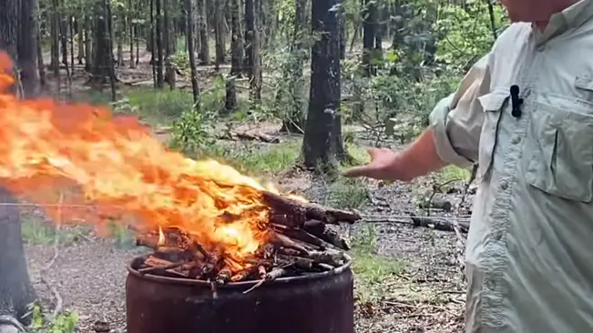 A person tending to a bright fire in a forest