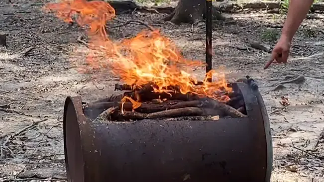 A person tending to a bright fire in an outdoor fire pit