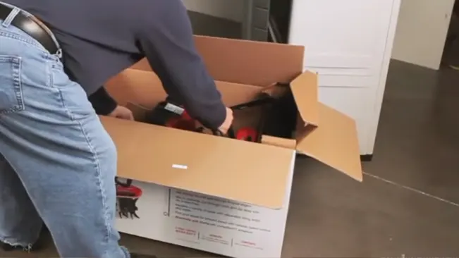 A person packing tools into a large cardboard box