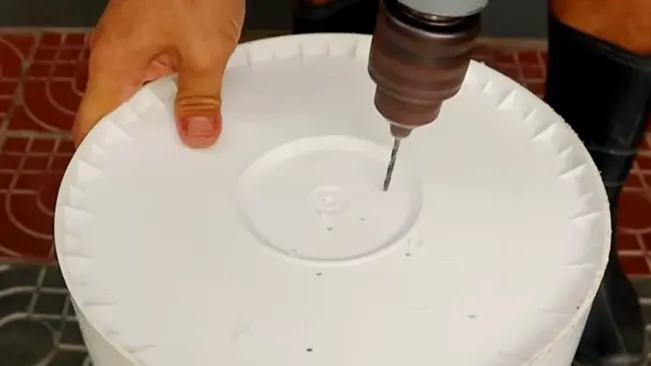 Person drilling hole in bucket