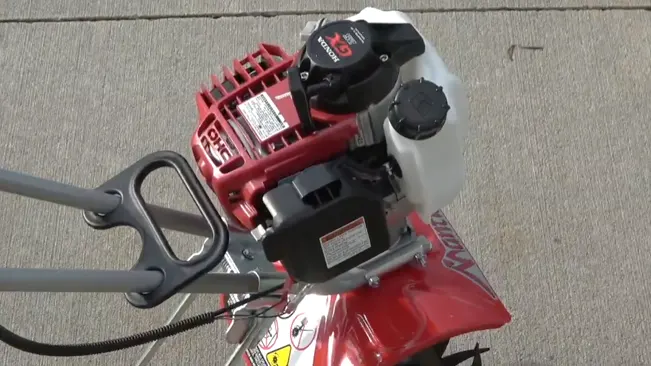 top view of a red and white gas-powered tiller on a concrete surface