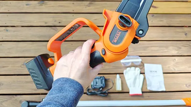 Person holding a cordless chainsaw on a wooden deck