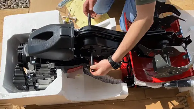a person assembling a black and red lawnmower engine outdoors