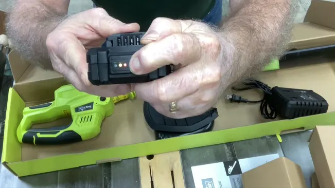 Person inserting a battery into a green cordless drill on top of an open box