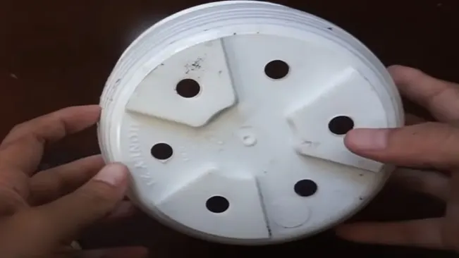 Hands holding the lid of a container with drainage holes