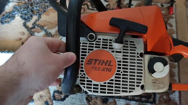 Person touching STIHL MS 210 Chainsaw laying in the table