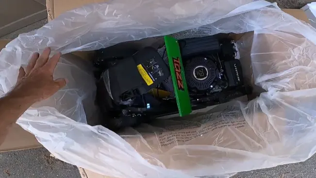 Hand unpacking a new black and green engine from a box