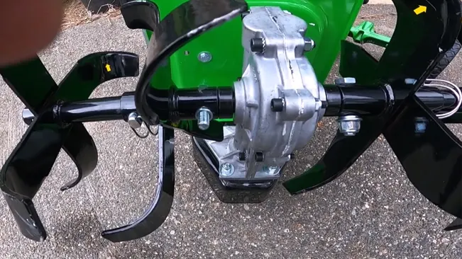 Close-up of a green and black tiller attachment with metal tines