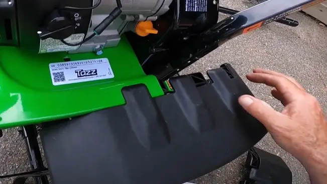 Person’s hand adjusting the black chute on a green Tazz wood chipper