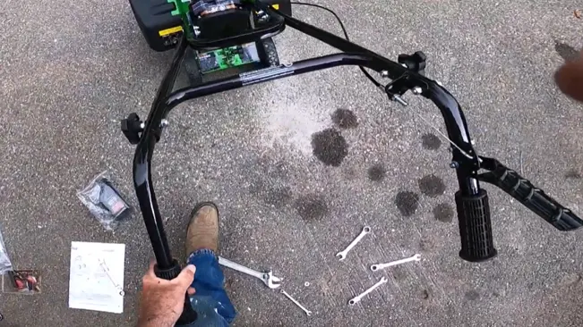 Person’s hands assembling a machine on a concrete floor with various tools