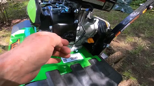 Person’s hand adjusting a green and black tiller engine