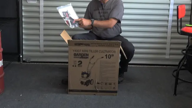 Person reading a manual next to a ‘Y4007 MINI TILLER CULTIVATOR’ box