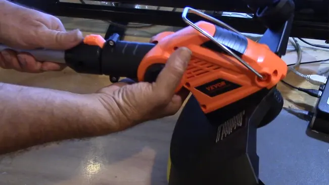 Hands holding an orange power tool