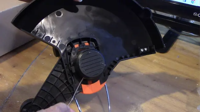 Person assembling a black and orange mechanical part