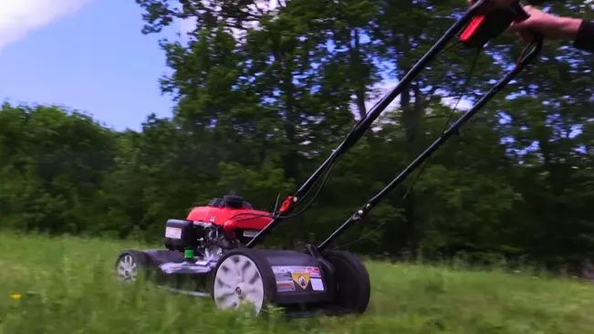 Person mowing grass with a TroyBilt lawn mower.