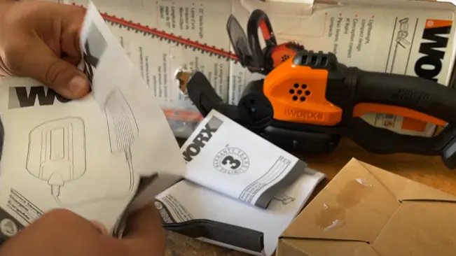 Person holding an instruction manual for a WORX chainsaw