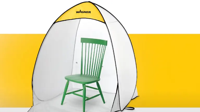
A green chair is positioned inside a Wagner Spraytech foldable paint spray booth, which is set against a yellow and white background, showcasing the booth's size and use case.